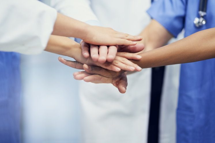 Closeup shot of a group of medical professionals standing in a huddle with their hands together